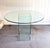 1970s Pace-style all glass round dining table w/ brass corner brackets. Can be configured in multiple ways with the 2-part...