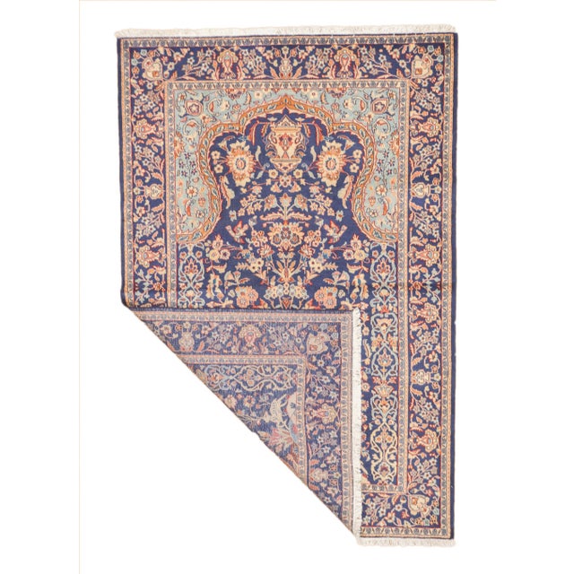 Semi-antique hand-knotted Persian Kashan rug with a vase and floral design on a navy field. The pattern shows a central...