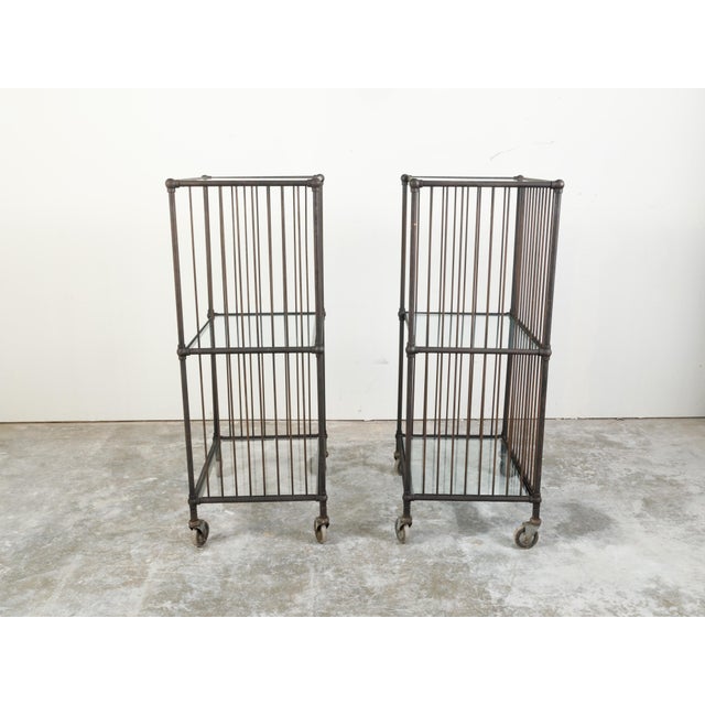 Two vintage industrial carts from the 20th century, with glass shelves and casters, priced and sold $5,400 each. Created...