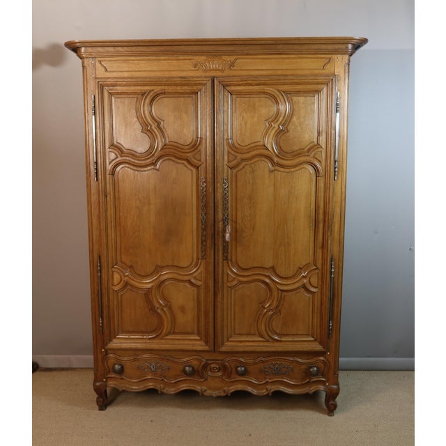 A carved and molded light oak wardrobe dating from the 18th century. It opens with two doors; the interior is fitted with...