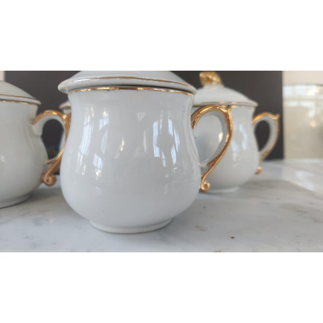 Vintage set of four lidded Pot de Creme by Strafford cups in glossy white porcelain with gilt handles, fine gold trim, and...
