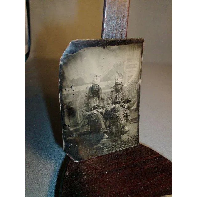 An interesting tintype of two men dressed in traditional native American Indian garb complete with headdress before...