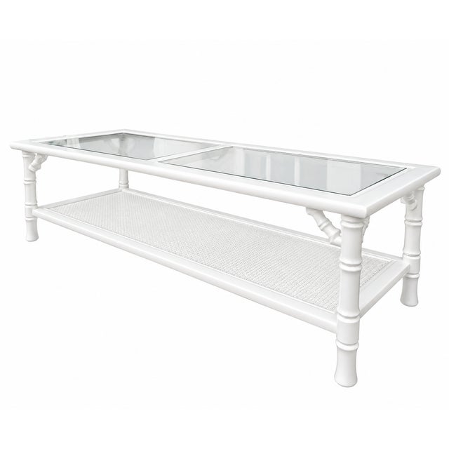 Vintage faux-bamboo coffee table featuring a two-panel inset glass top, bamboo-inspired detailing, and a generous lower...