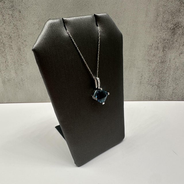 This elegant topaz and diamond necklace in 10kt white gold features a striking cushion cut checkerboard top London blue...