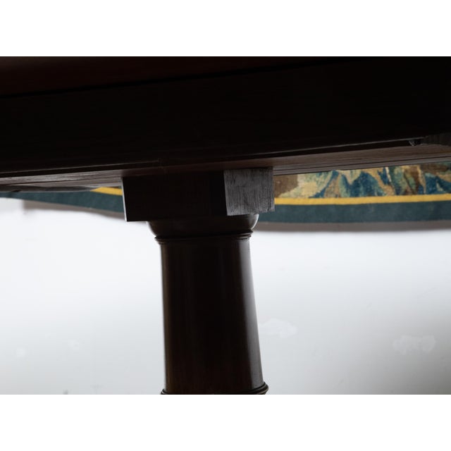An English mahogany pedestal table from the Mid-19th Century, with oval top, cross banding, quadripod base and brass...