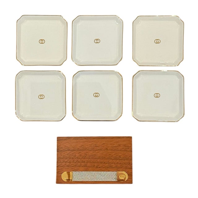 Gucci Ashtray or Coaster Set with Wooden Holder. 6 ceramic coasters with a Gucci holder. White porcelain with gilded edges...