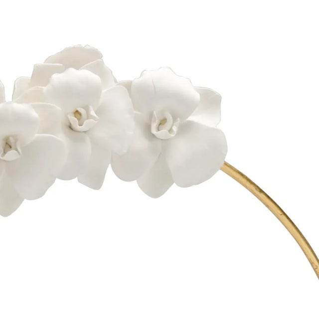White ceramic orchid on antique gold painted iron stem mounted on clear crystal.