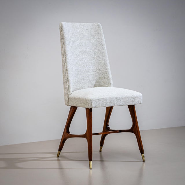 Set of six dining chairs from the 1950s featuring gently shaped frames in dark-stained wood with brass sabots. The rounded...