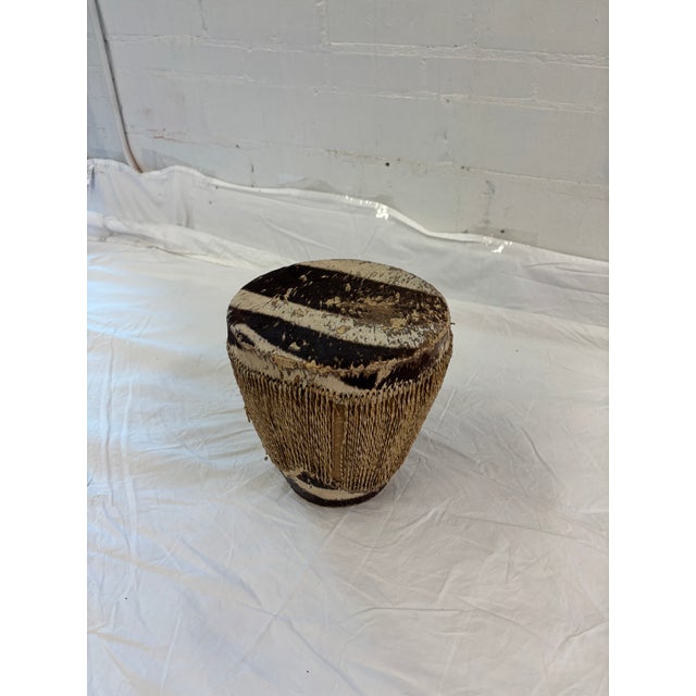 Vintage handmade African tribal drum featuring a natural hair-on animal hide drumhead and a tapered body wrapped in woven...