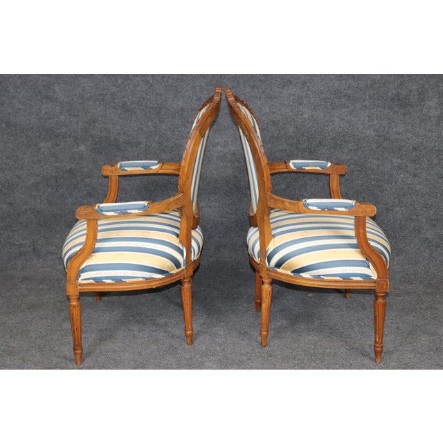 This elegant pair of early 1900s French Louis XVI style oval-back fauteuils beautifully captures the refined elegance and...