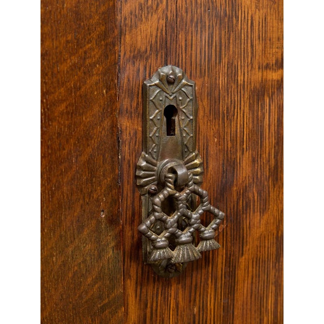 A handsome antique armoire with a tall architectural silhouette and richly figured wood grain throughout. The front is...