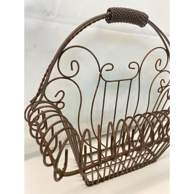 A charming vintage iron wire basket planter with ornate Victorian-style scrollwork and decorative handle. Its flat back...