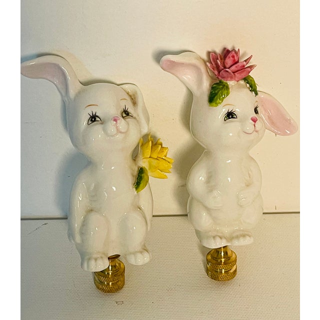 Whimsical glazed porcelain rabbit pair mounted on brass bases as lamp finials.