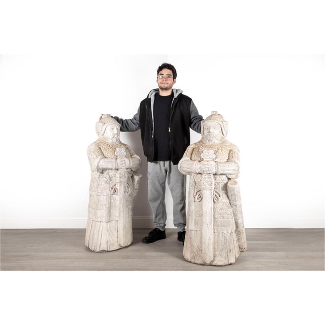 A pair of large intricately carved stone statues depicting Chinese court dignitaries or military officials in traditional...