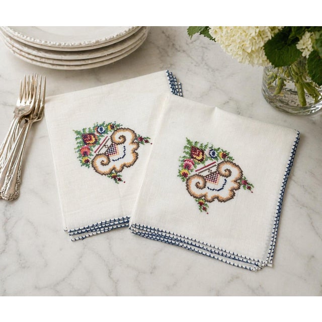 Vintage hand-embroidered cotton dinner napkins featuring delicate cross-stitch floral motifs and distinctive blue stitched...