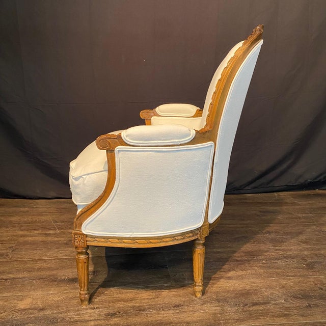 Elegant pair of 19th century French Louis XVI fauteuils featuring finely carved walnut frames with oval backs, fluted...