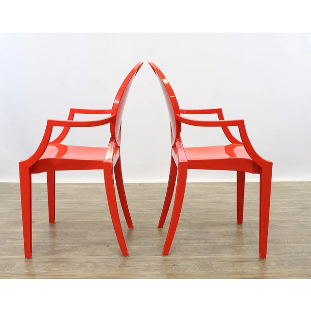 Set of four molded plastic armchairs in red, after the “Louis” chair design by Philippe Starck for Kartell. Produced in a...