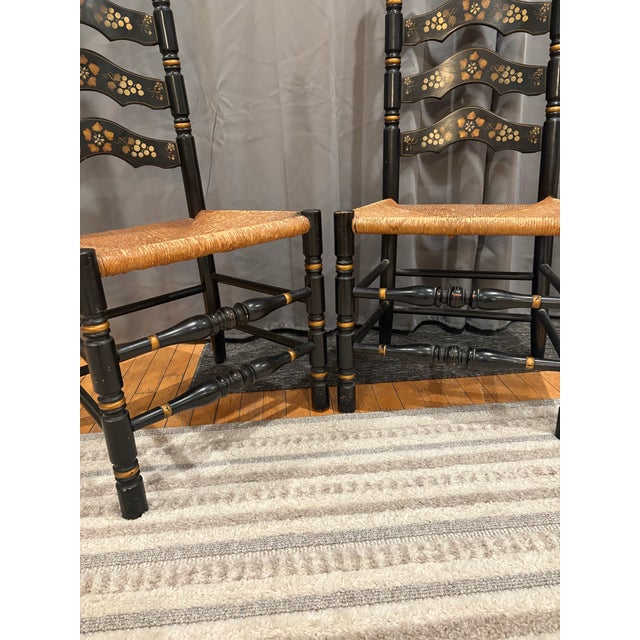Charming pair of vintage dining chairs in the iconic Hitchcock style, featuring a glossy black finish with hand-stenciled...