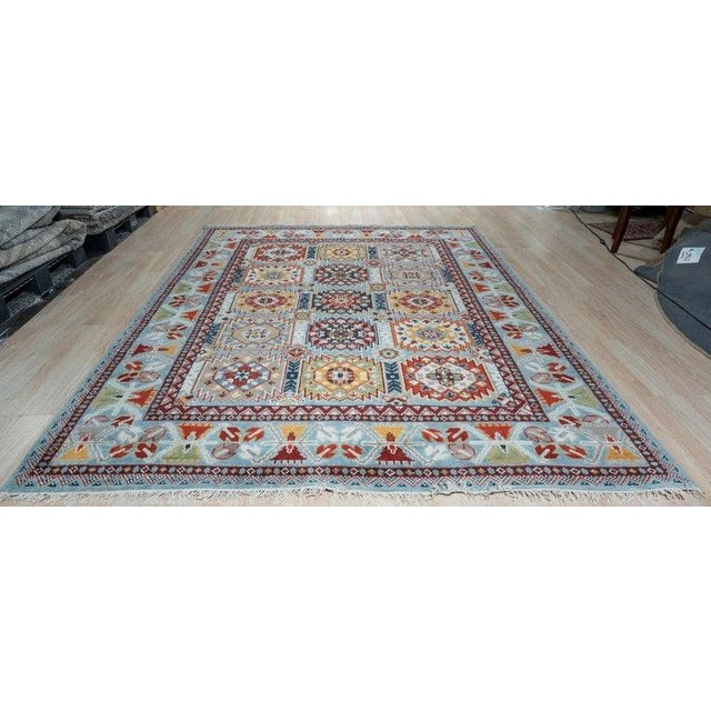 This blue wool area rug features a hand knotted pile construction suitable for a variety of residential environments. The...