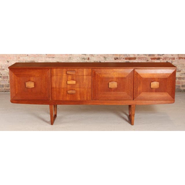 A midcentury teak sideboard by stonehill furniture, dating to the 1960s. The piece features a balanced layout split into...