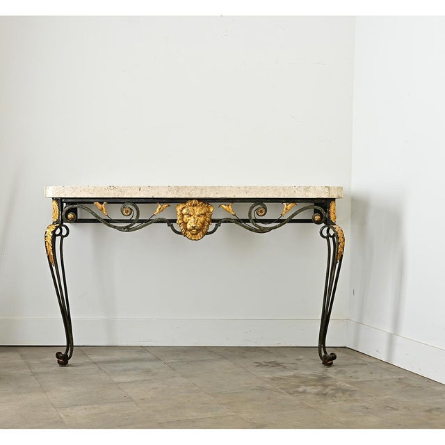 A French 19th century wrought iron console with thick limestone top and parcel gilt decoration around the table frame to...
