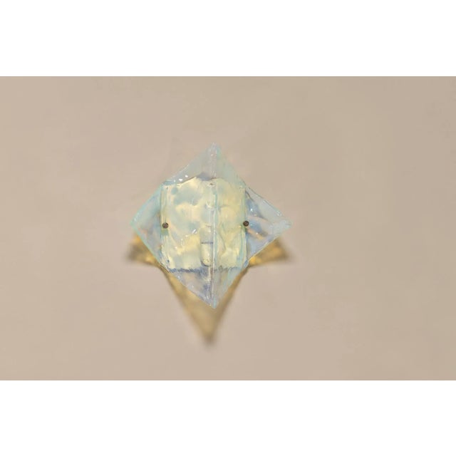 The shape of this wall lamp is reminiscent of a folded piece of paper and is made of a Murano glass type or technique...