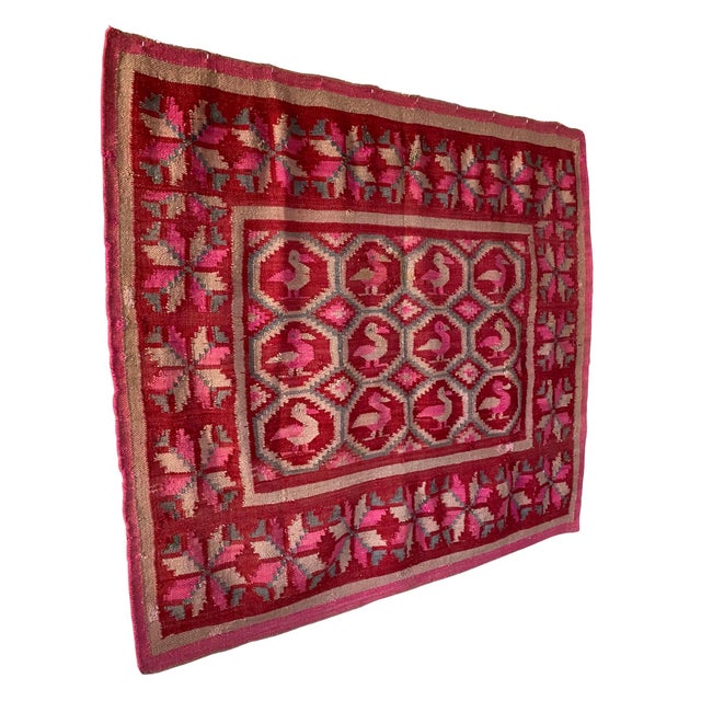 This vintage Peruvian textile features a striking field of stylized bird motifs, arranged in a geometric grid and framed...