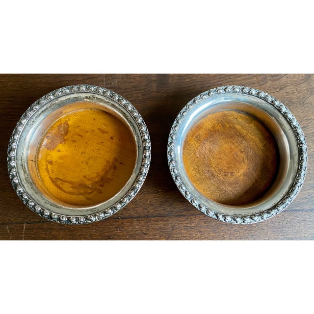 This is a lovely pair of German 800 silver bottle coasters with embossed roses encircling concave sides and wooden bottoms...