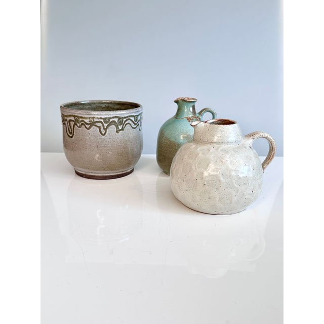 This harmoniously arranged trio, consisting of two vase-jugs and a cachepot, each with its own unique color and glaze...