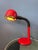 A striking red space age table lamp featuring a flexible metal arm and matching adjustable shade. Both the arm and shade...