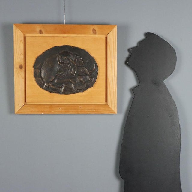 Oval bronze bas-relief depicting a seal tenderly embracing her pup. The artist's signature is engraved at the bottom....
