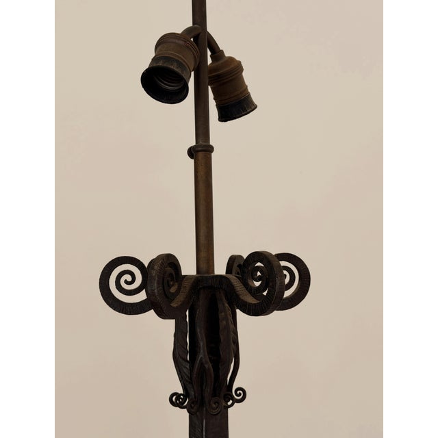 French hand hammered iron floor lamp in the Art Deco style. The tall, slender form is accented by a decorative finial and...