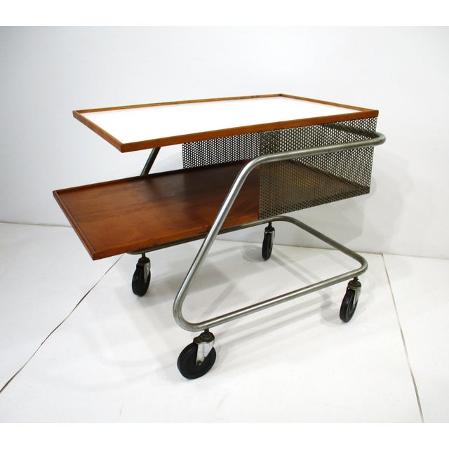A rare Mid Century industrial styled rolling bar cart with sculptural metal tubed frame with upper Laminate top and lower...