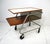 A rare Mid Century industrial styled rolling bar cart with sculptural metal tubed frame with upper Laminate top and lower...