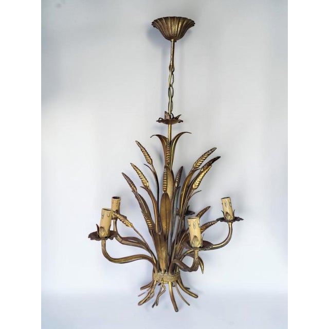A gilt metal pendant light in the Hollywood Regency style by Hans Kögl, late 1960s/early 1970s. This five-light model...