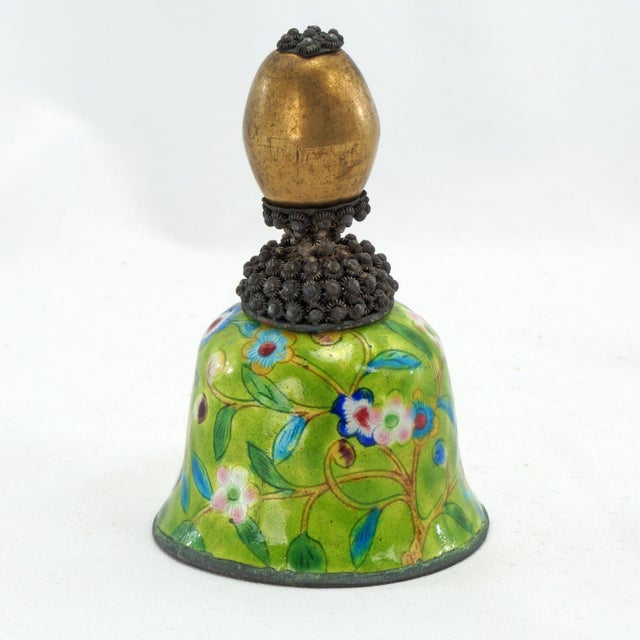 An antique Chinese enameled metal bell with a handle made from a repurposed Mandarin bronze hat finial. A thin metal has...