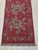 Vintage handwoven kilim runner featuring a rich brick-red background adorned with charming oversized floral motifs in soft...