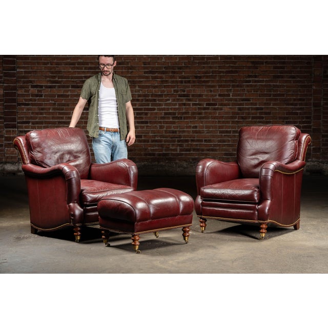 Vintage three-piece burgundy seating set. This elegant set includes two traditionally styled leather armchairs and a...