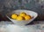 "Quiet Lemons" is an oil on panel painting by Jon Doran, completed in 2026. A wide white bowl holds a cluster of bright...