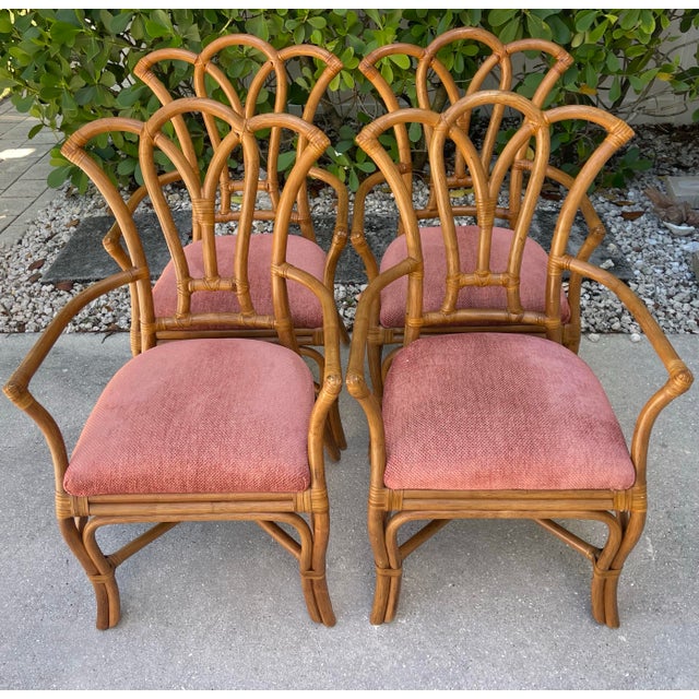 Set of four vintage rattan dining chairs featuring a sculptural fan back design with gracefully curved supports and hand-...