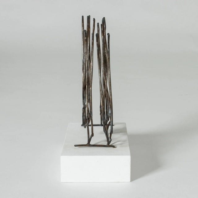 Sculpture with the title “Bathers” by Fred Leyman. Made from iron, mounted on a white wooden base. Waves and legs pointing...