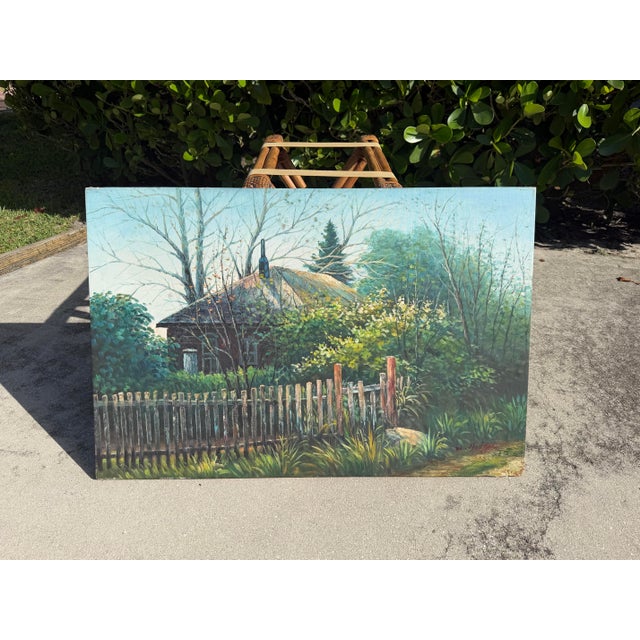 Original vintage landscape painting depicting a rustic cottage surrounded by mature trees, lush garden growth, and a...