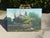 Original vintage landscape painting depicting a rustic cottage surrounded by mature trees, lush garden growth, and a...