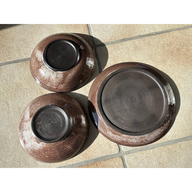 This set of two serving bowls and one serving plate from Serocka combines the workshop's signature warm earth tones, a...