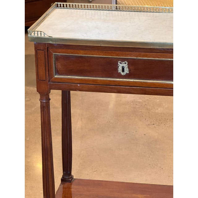 A elegant 19th century French mahogany side table with a pierced brass gallery top and brass molding along the top edge. A...