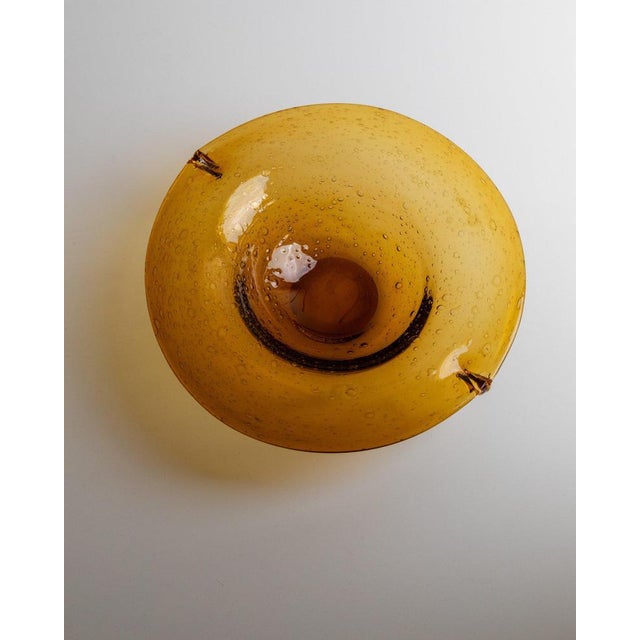 This vintage Murano glass bowl from the 1970s impresses with its elegant amber colour and the bubbles enclosed in the...