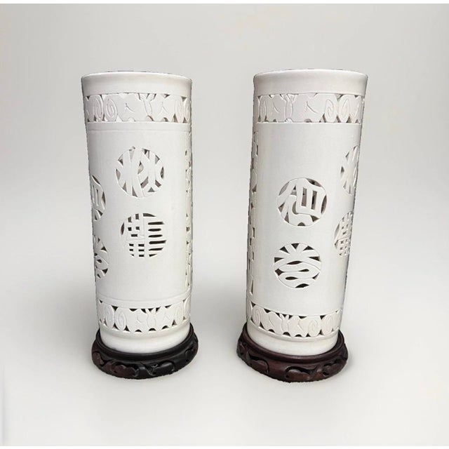 This listing features two vintage Blanc De Chine Chinese reticulated porcelain vases with wooden stands. These medium-...