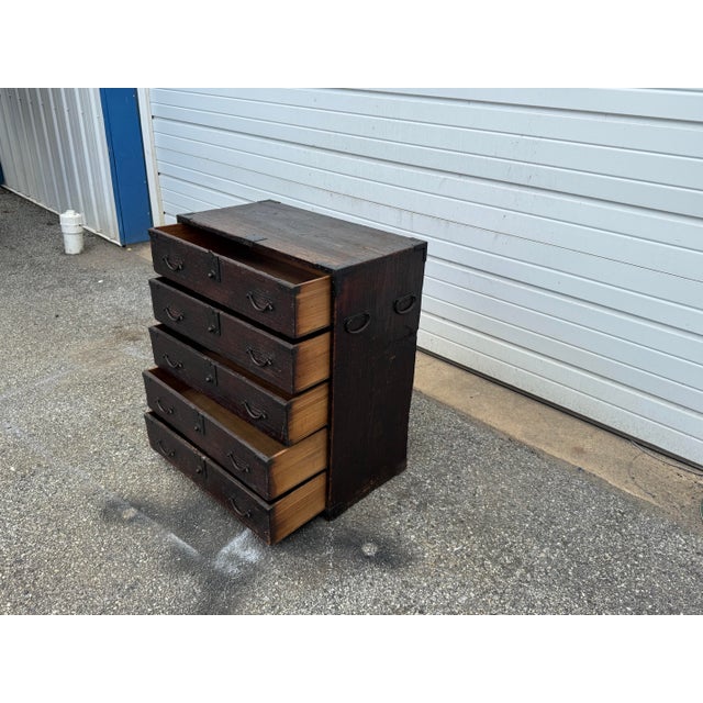 A striking vintage pine campaign chest featuring five full-width drawers and extensive iron hardware throughout. The chest...
