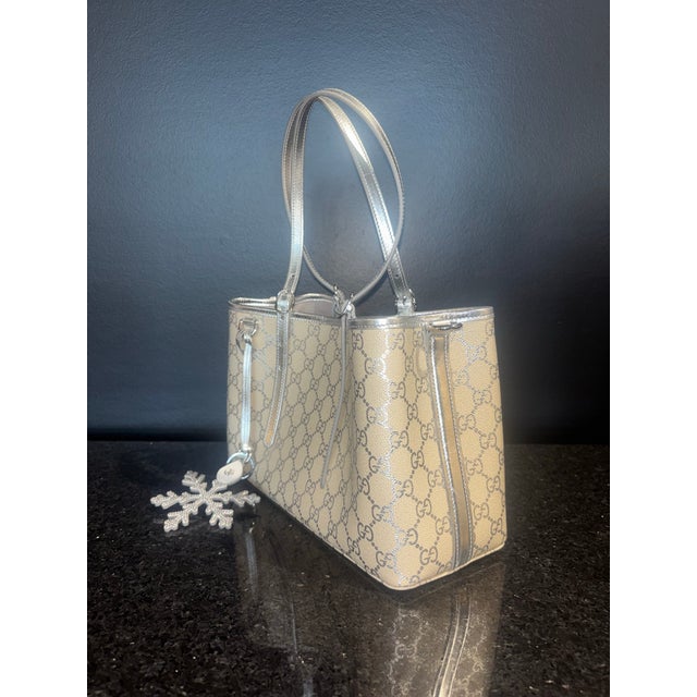 This striking Gucci small tote offers a luminous twist on classic Italian luxury. Crafted from durable, coated canvas, the...