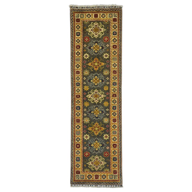 This natural dye wool runner features a charcoal gray field with a row of colorful Kazak-style geometric motifs. A cream...